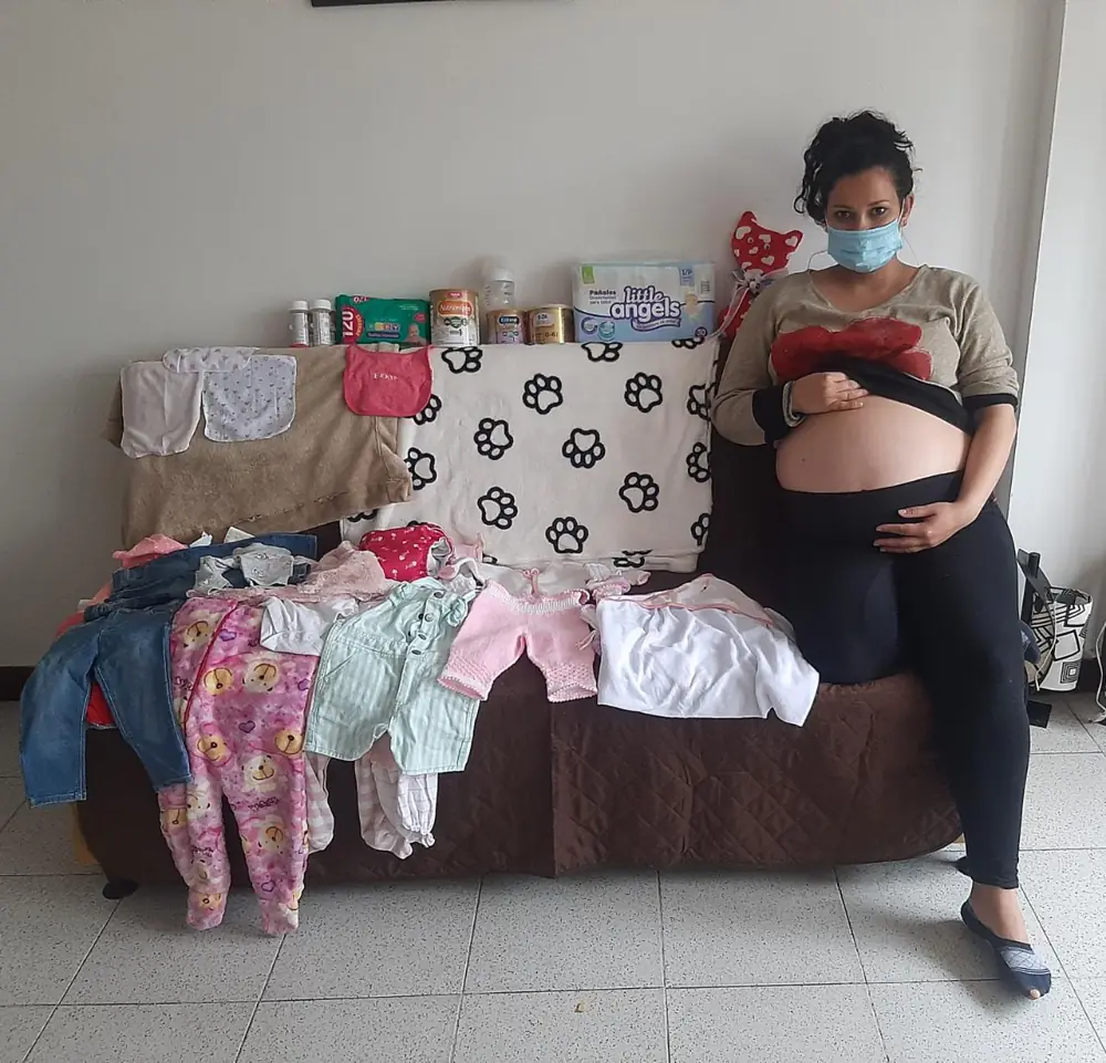 Mamá gestante con ropa para su bebé