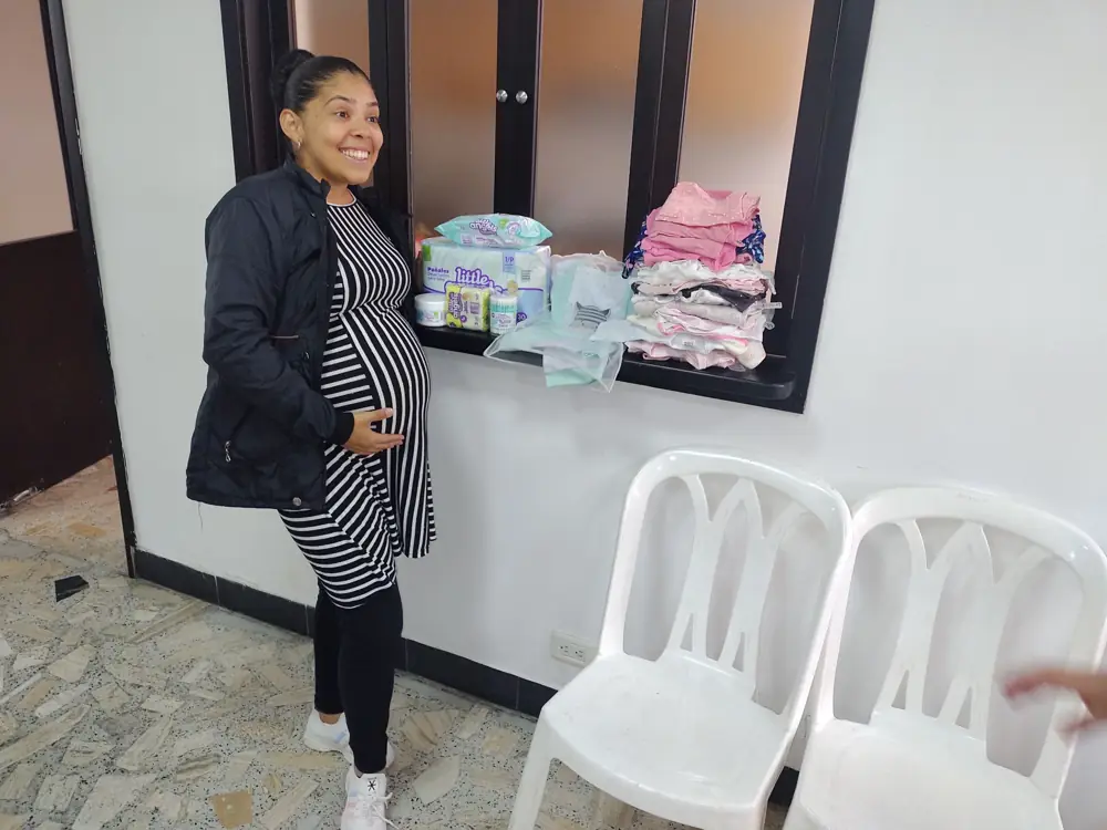Mamá gestante con la ropa que recibió para su bebé