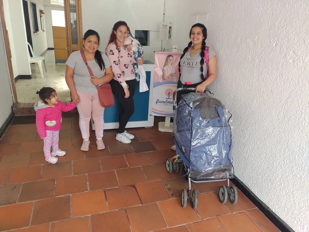 Una mamá con sus hijos y el coche de su bebé