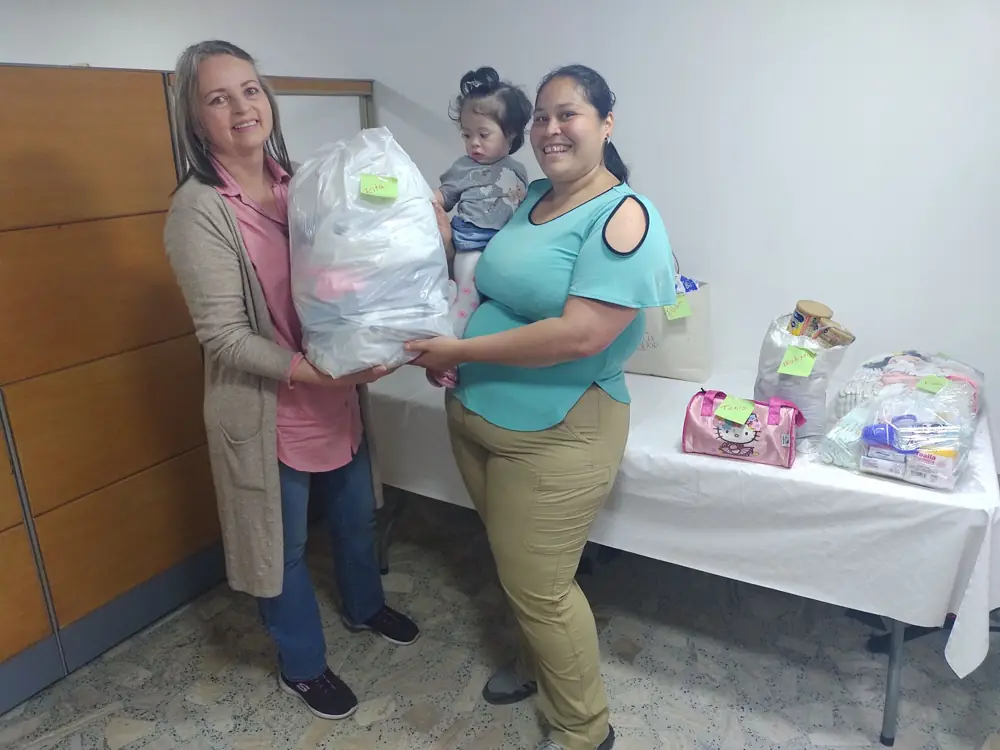 Una voluntaria entrega una donación a una mamá