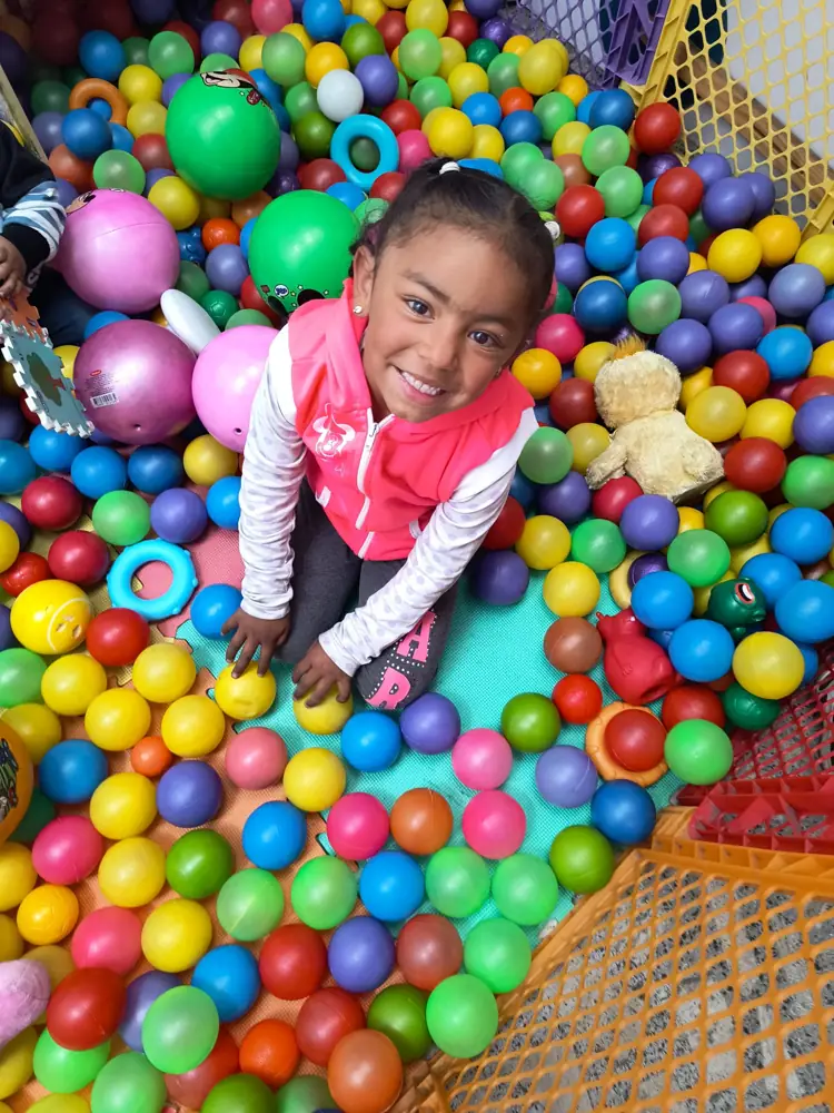 Niña feliz en la piscina de pelotas
