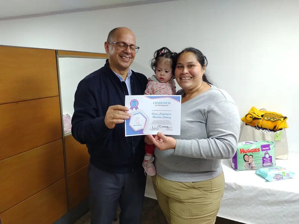 Una mamá recibe su certificado con su bebé en brazos